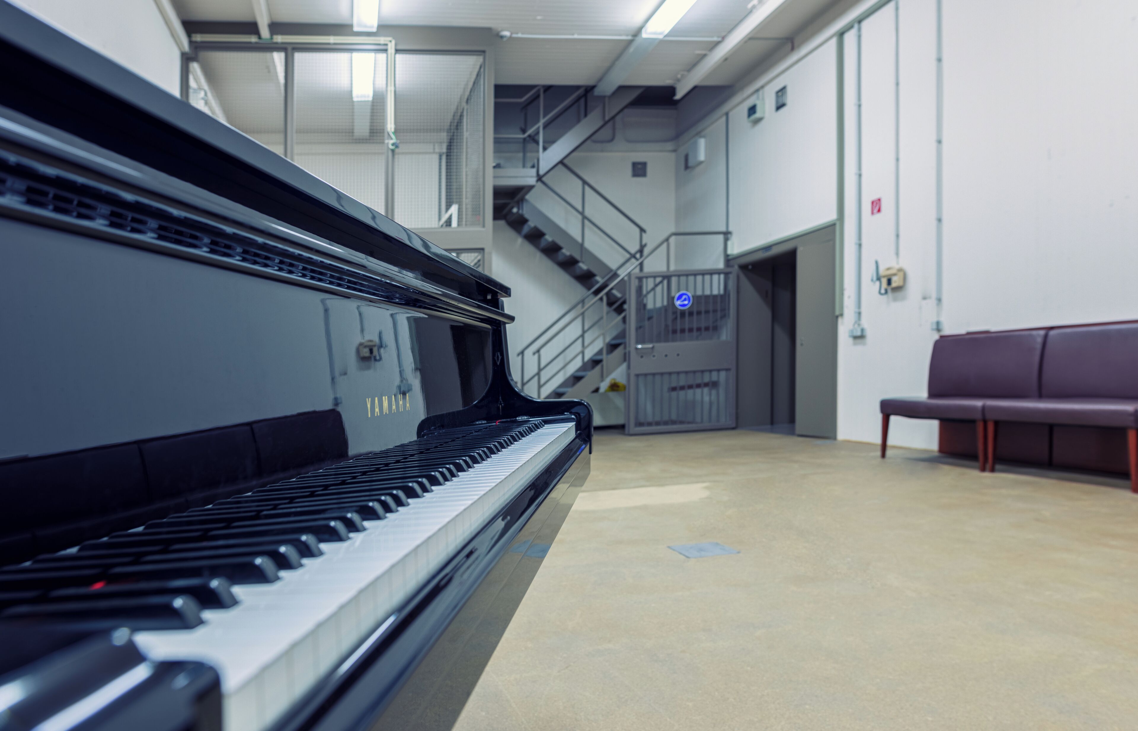 Un pianoforte a coda in una stanza ampia, con una scala e una panca.