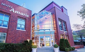A hotel with a prominent glass entrance, a brick facade, and a sign reading 'HOTEL Amaris'. -  Hotel Amaris Bremerhaven (Bremerhaven)