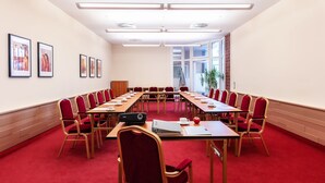 A conference room with a long table, red chairs, and framed artwork on the walls. - Hotel Amaris Bremerhaven (Bremerhaven)