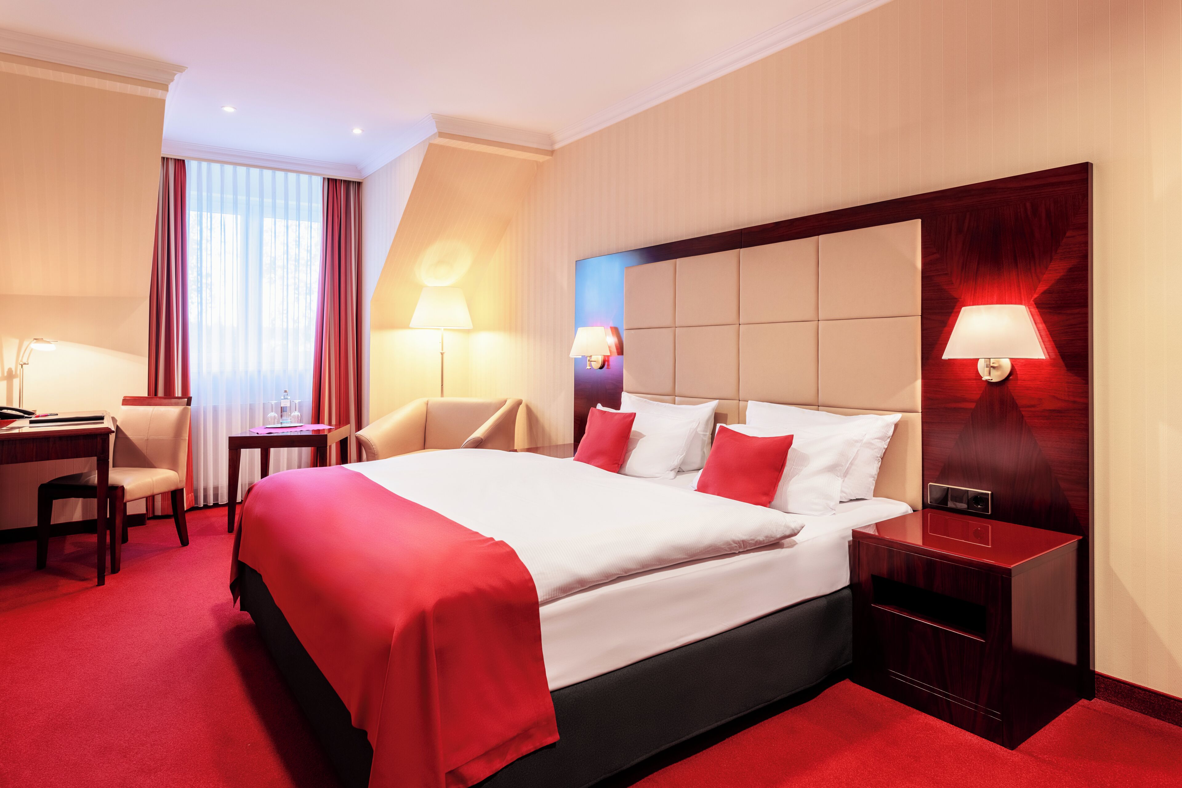 Camera d'albergo con un letto grande, due comodini, una scrivania e una sedia.