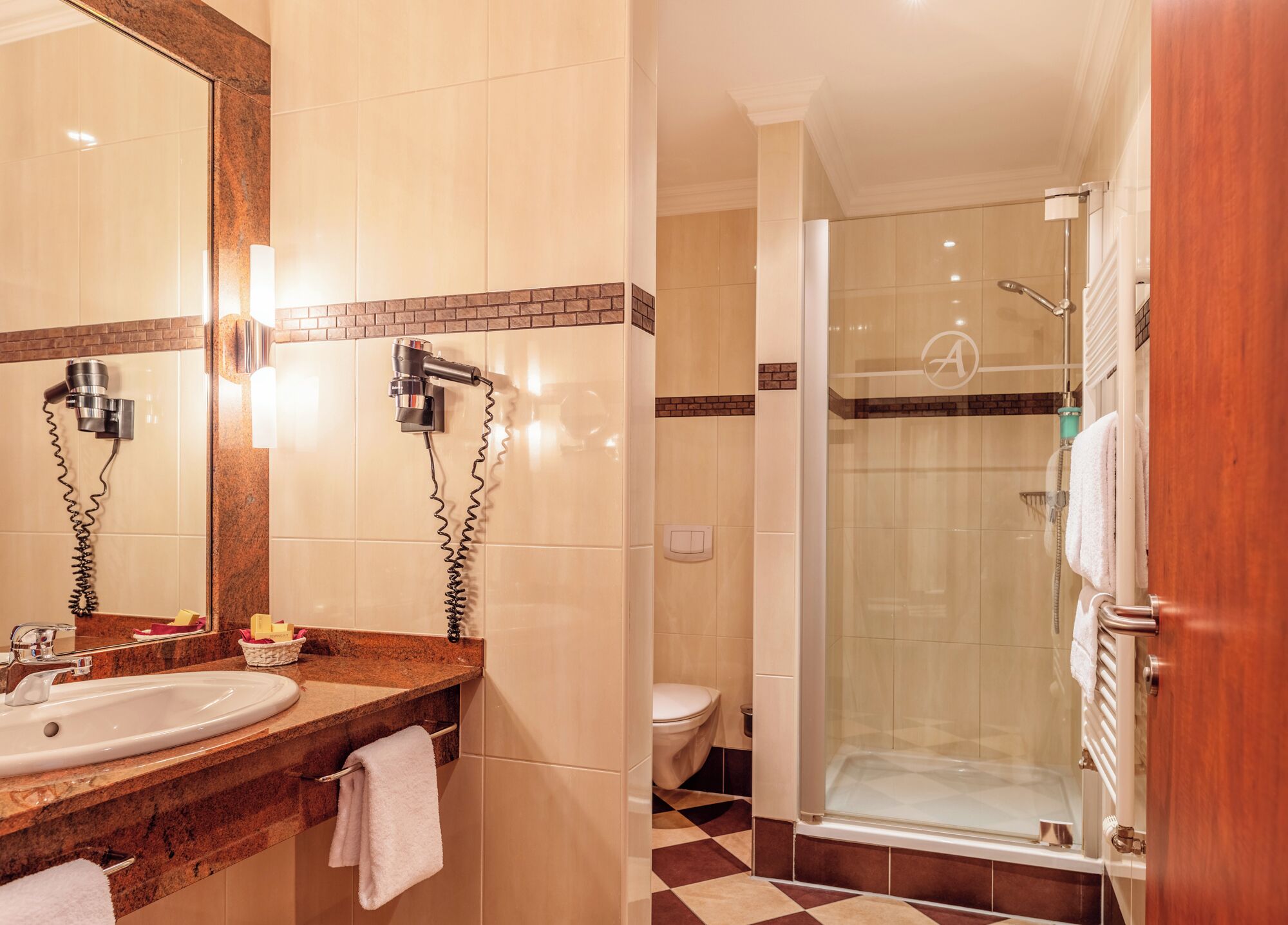 A hotel bathroom with a sink, mirror, towel rack, and a shower area.