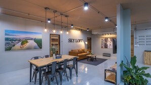 A modern interior with a dining area, a sofa, and a large painting of a bridge. - Otter House (Krabi)