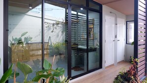 A modern interior with a sliding glass door leading to a balcony, a white door, and a wooden structure on the right. - Otter House (Krabi)