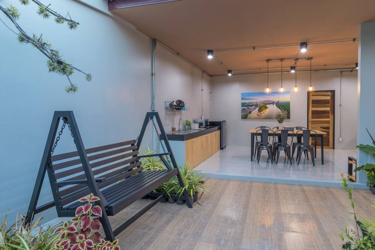 A modern kitchen with a dining area, wooden flooring, and a hanging swing chair.