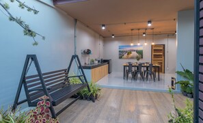 A modern kitchen with a dining area, wooden flooring, and a hanging swing chair. - Otter House (Krabi)