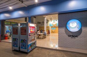 A restaurant with a blue exterior and a sign featuring a cartoon otter. Inside, there are tables with people dining. - Otter House (Krabi)