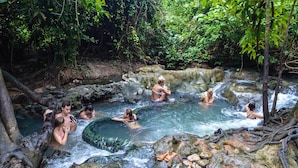 A natural hot spring with clear water surrounded by rocks and trees. - Otter House (Krabi)
