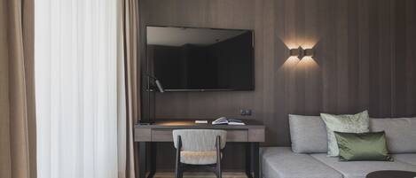A modern room with a desk, chair, and a large flat-screen TV mounted on the wall.
