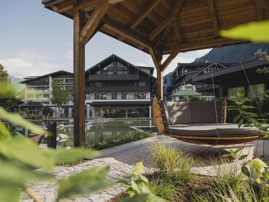 A wooden outdoor seating area with a view of modern buildings and a body of water.