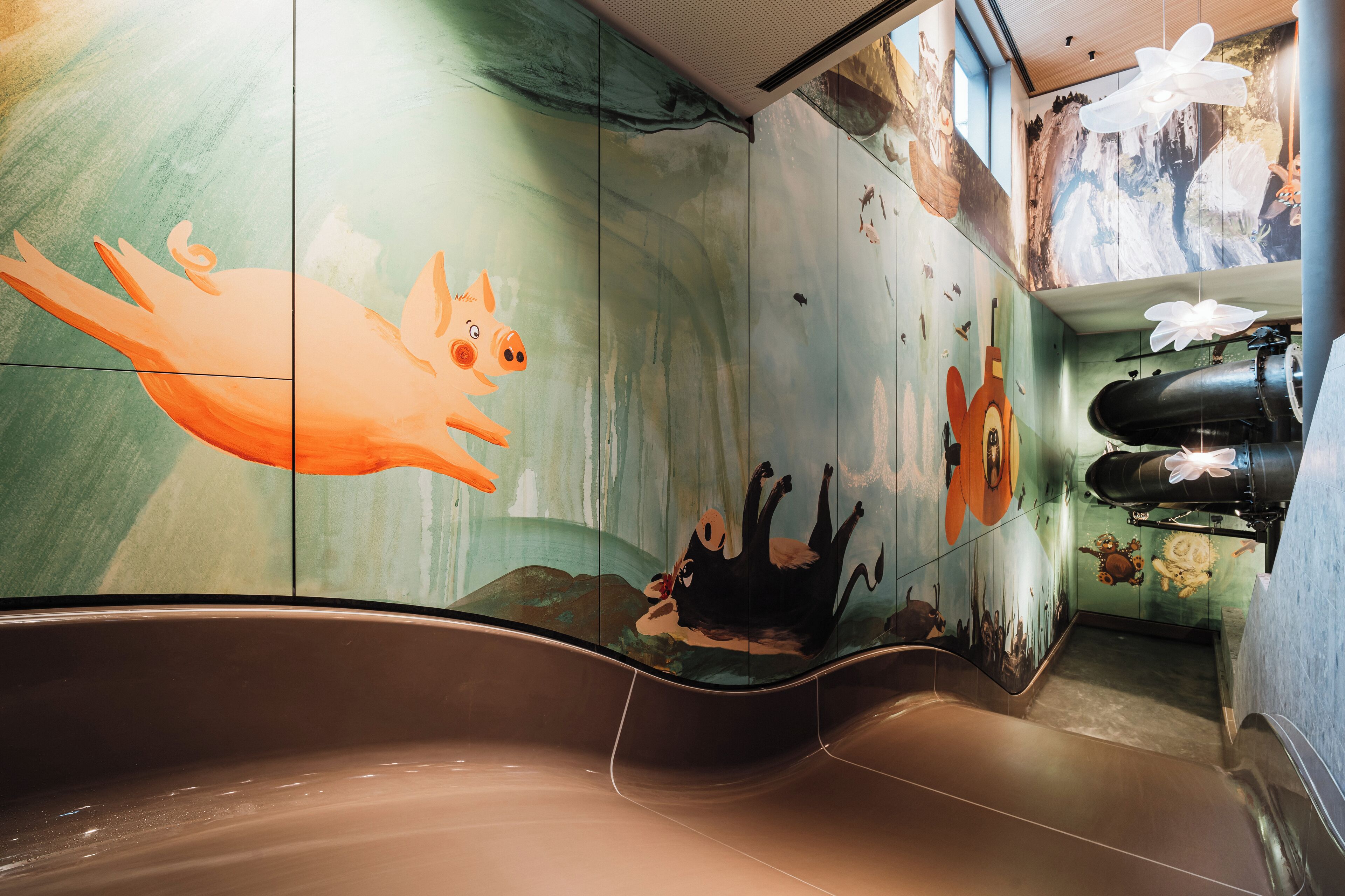 Un baño moderno con una bañera grande, un mural con una rana y un perro, y una zona de ducha con una manguera negra.