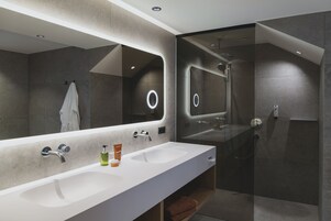 Une salle de bain moderne avec un grand miroir, deux lavabos et un espace douche.