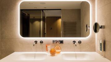 Un baño moderno con un espejo grande, dos lavamanos y un perchero para toallas.