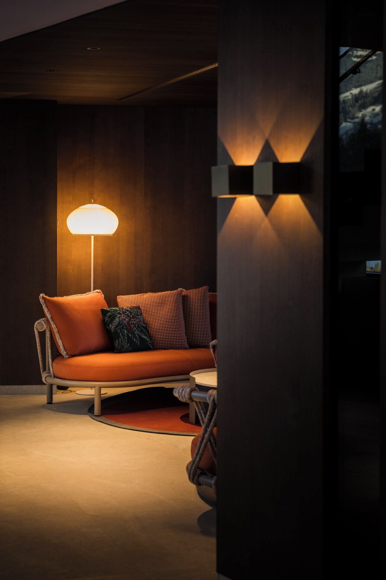 A modern living room with a sofa, a floor lamp, and a wall-mounted light fixture.