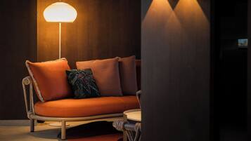 A modern living room with a sofa, a floor lamp, and a wall-mounted light fixture.