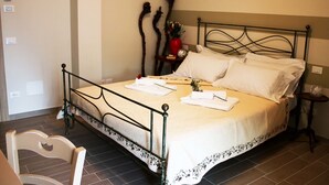 A neatly made bed with white linens, a metal headboard, and a bedside table with a vase of flowers. - B&B Corte Galo (Tregnago)
