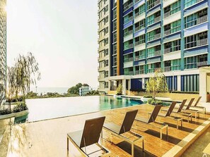 A hotel with a pool area, lounge chairs, and a view of the ocean. - Lumpini Parkbeach Jomtien Sea&Pool View by Dome (Pattaya)