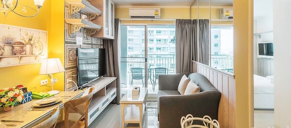 A compact living space with a sofa, TV, dining area, and balcony with city views. - Lumpini Parkbeach Jomtien Sea&Pool View by Dome (Pattaya)