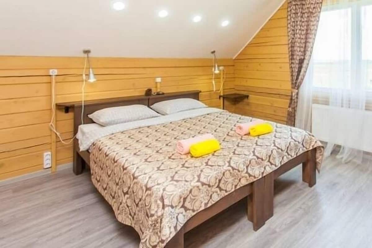 A bedroom with a wooden headboard, a patterned bedspread, and two bedside lamps.