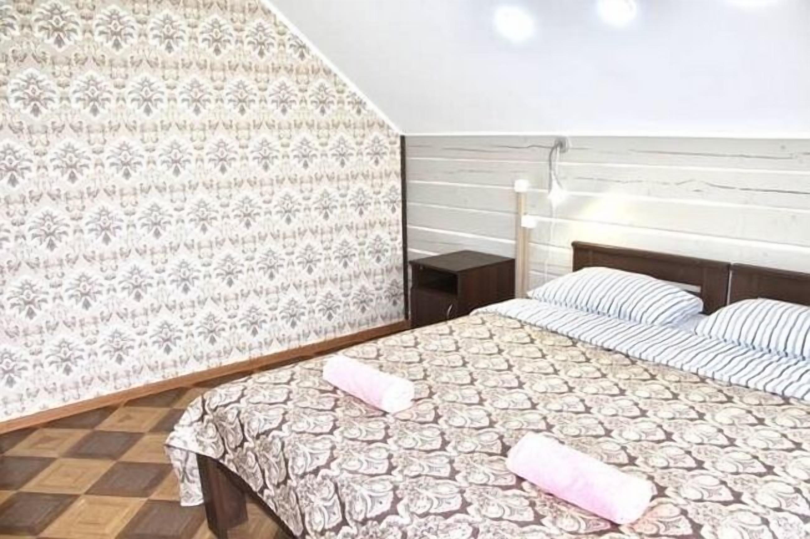 Un dormitorio con pared estampada, una cama con ropa de cama a rayas y una mesita de noche con una lámpara.