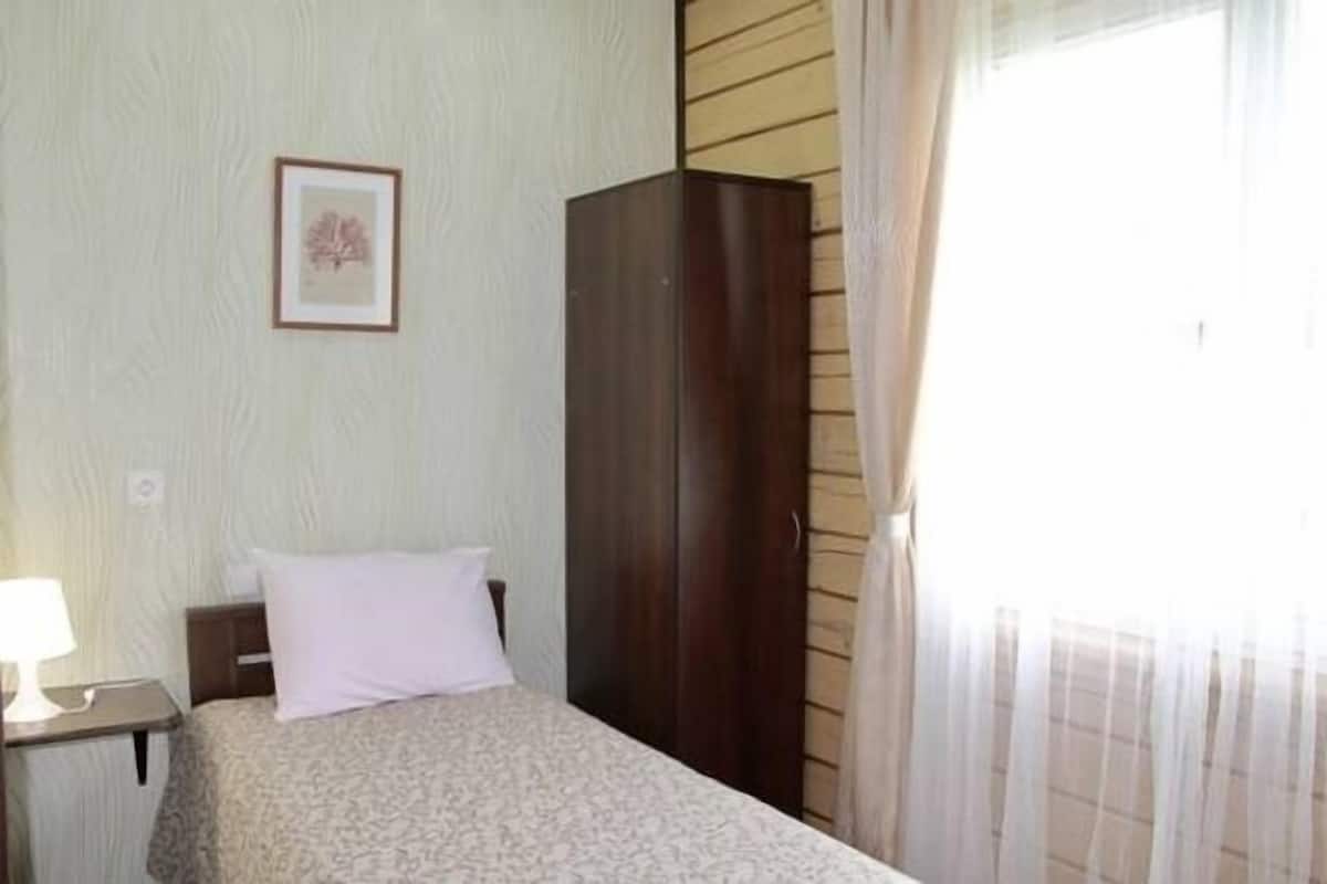 A bedroom with a bed, a nightstand, a wardrobe, and a framed picture on the wall.
