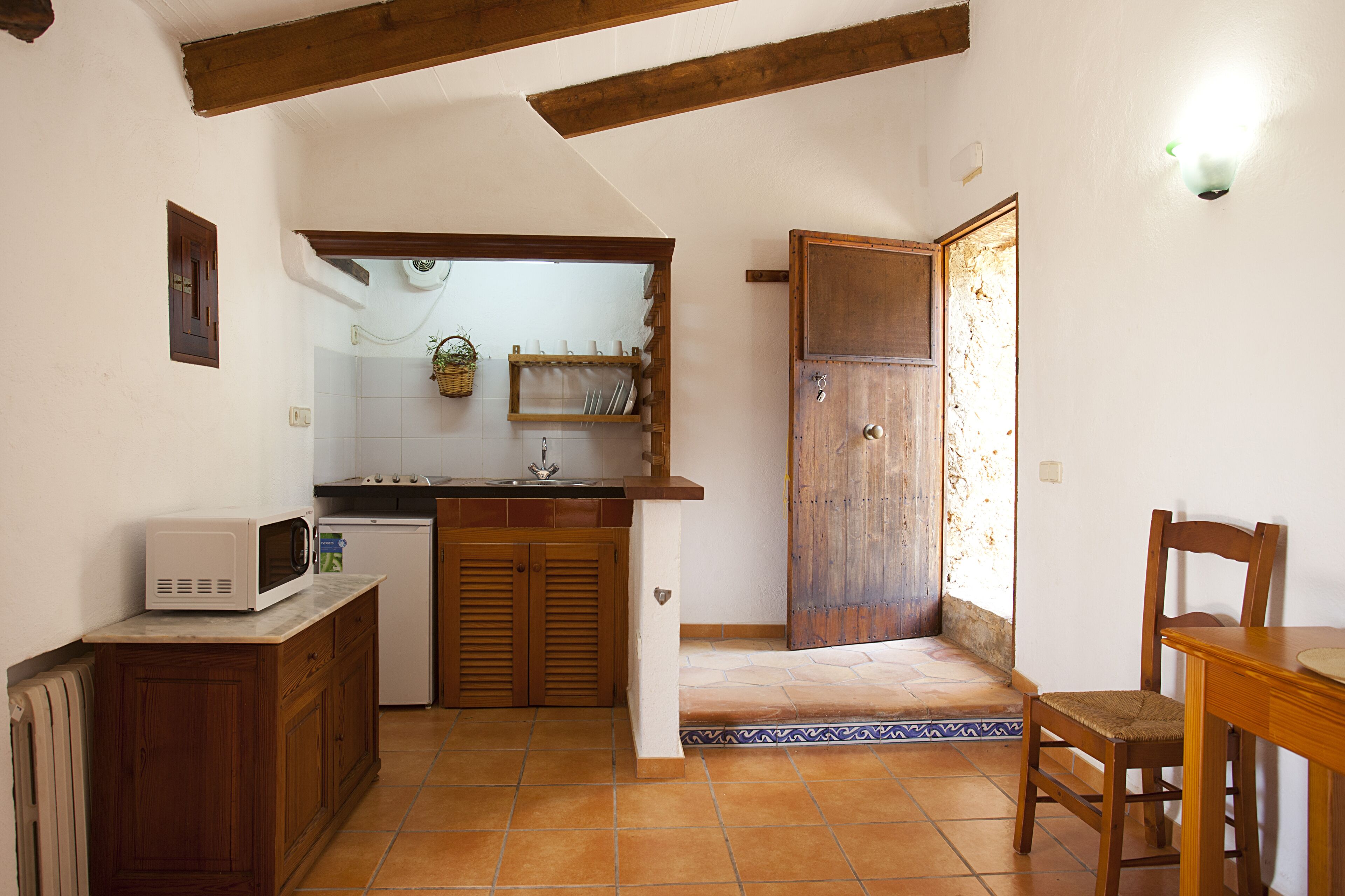 Una cocina compacta con armarios de madera, un microondas y piso de baldosas.