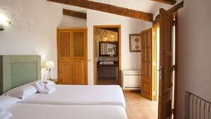 A hotel room with a bed, a wooden wardrobe, a bathroom with a mirror, and a door leading to another room. - Agroturismo Finca Son Sureda (Manacor)