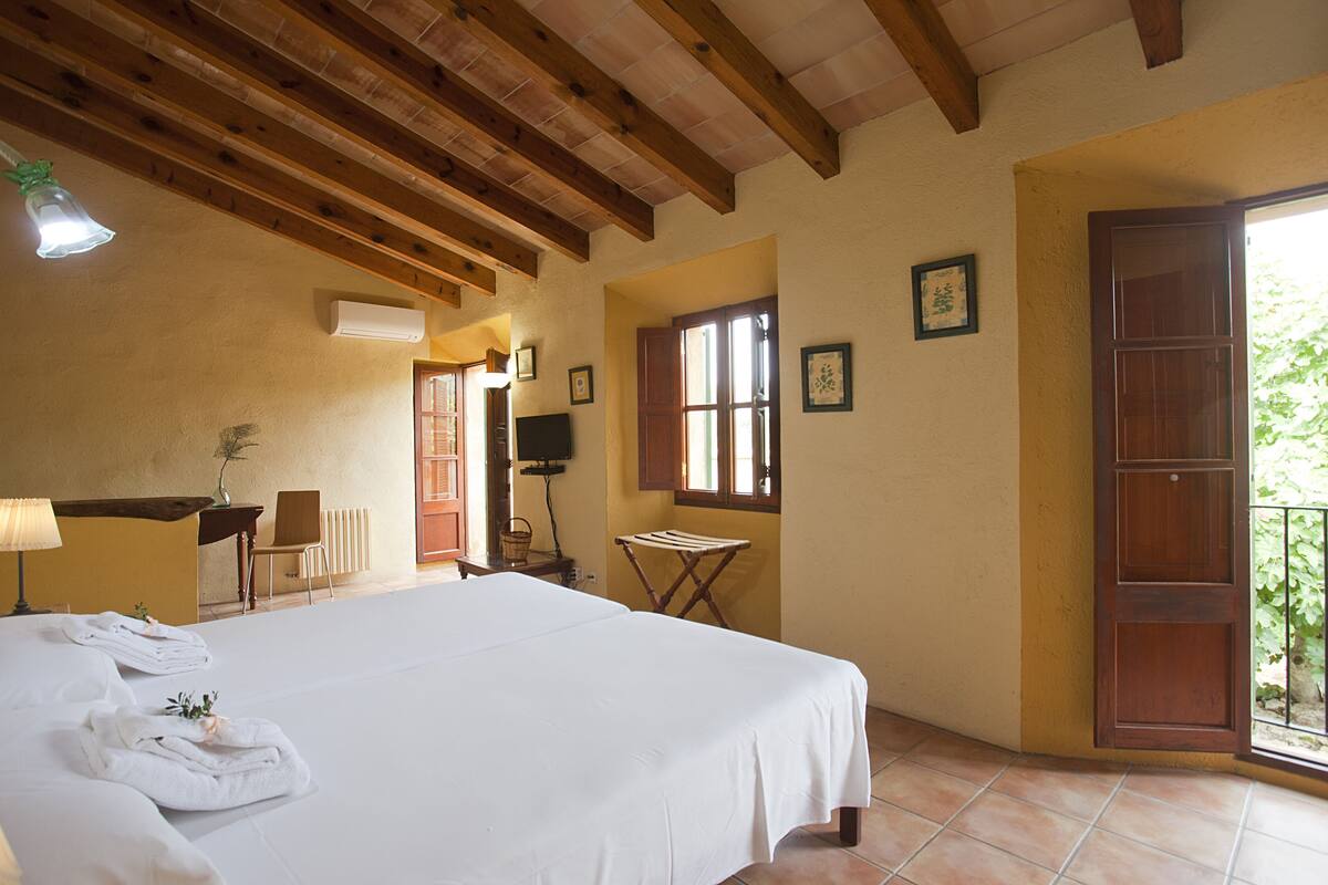 Une chambre d’hôtel avec un lit, un bureau, une chaise, une télévision et une fenêtre.