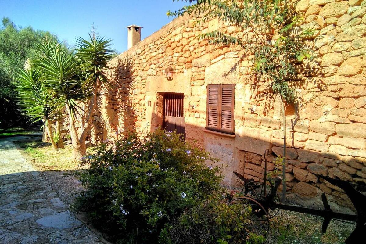 Un bâtiment en pierre à l’aspect rustique, doté d’une fenêtre avec des volets en bois et d’une cheminée.