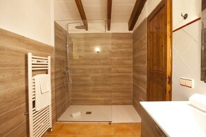 Ein modernes Badezimmer mit einer gläsernen Duschkabine, Holzvertäfelung und einem weißen Waschbecken.
