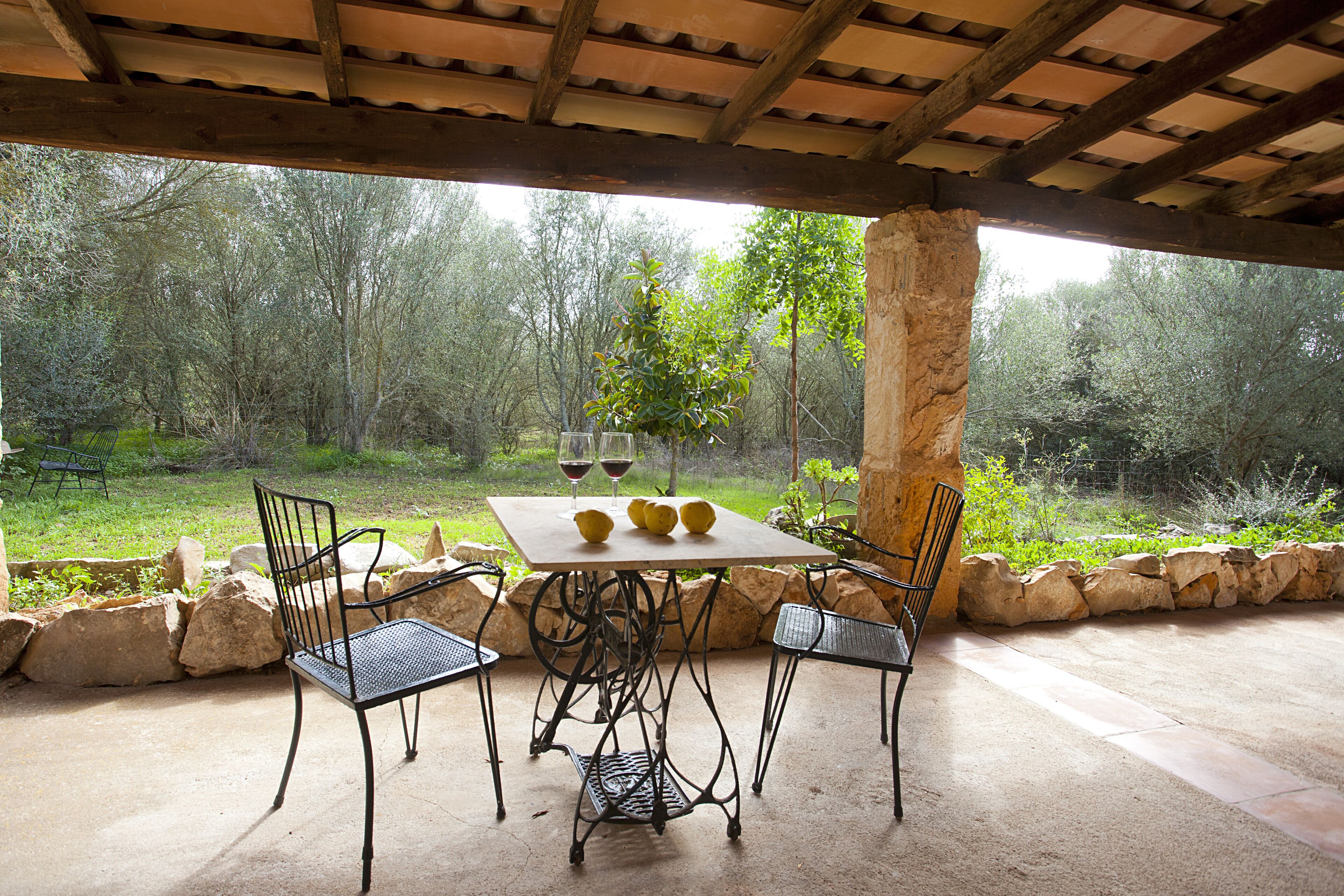 Un patio al aire libre con una mesa, sillas y vistas a un bosque.