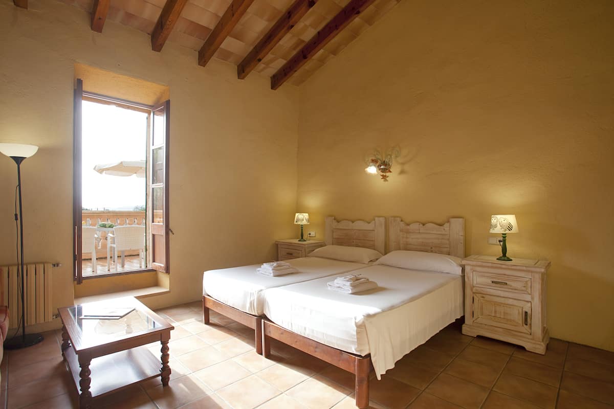 Une chambre avec deux lits, une table de chevet avec des lampes, une table et une vue sur l’extérieur.