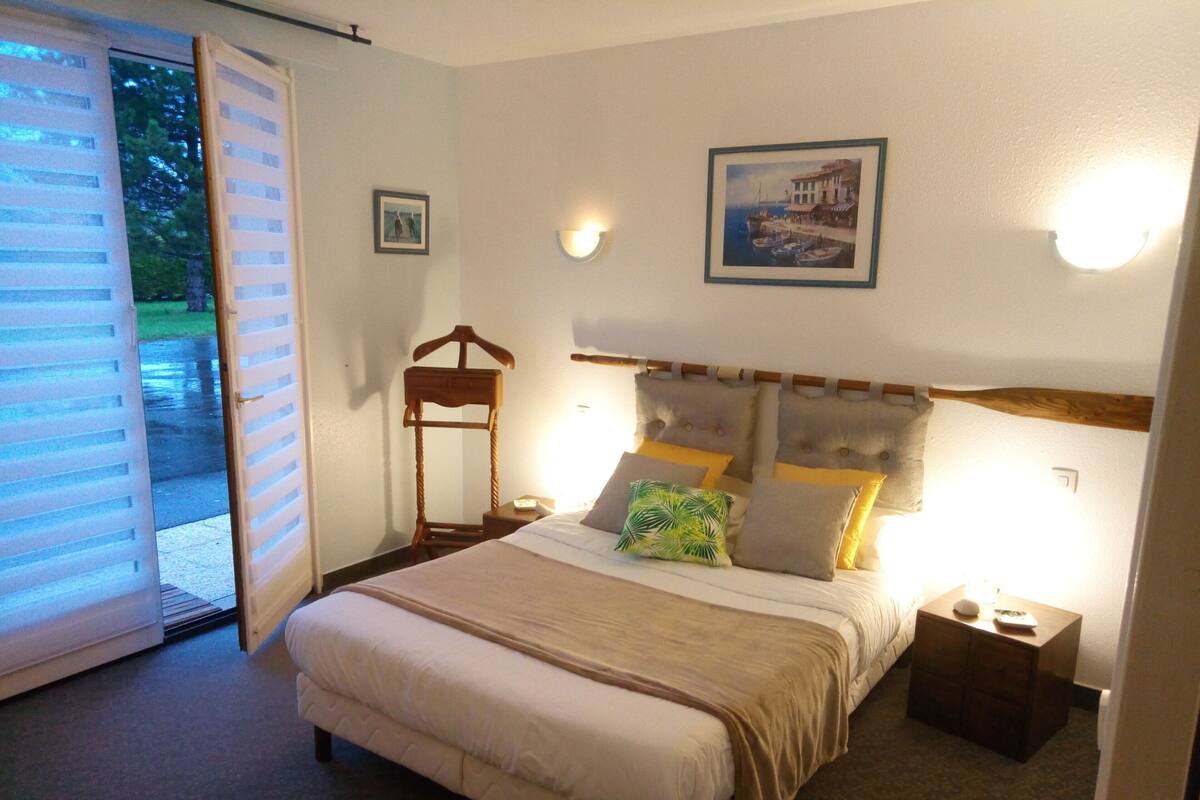 A bedroom with a bed, bedside tables, a wooden chair, and a picture on the wall.
