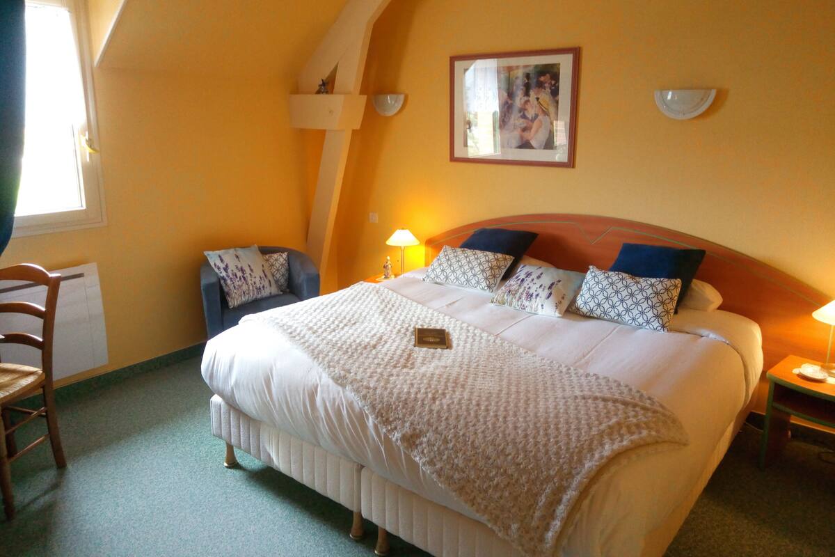 A hotel room with a large bed, a chair, a desk, and a window.