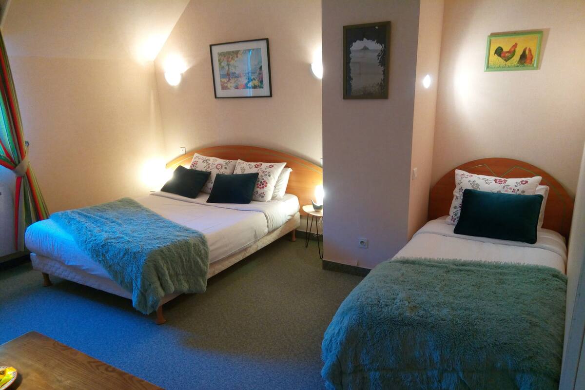 A hotel room with two single beds, a small table, and a chair.