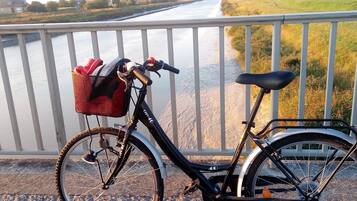 A bicycle parked by a river with a basket and a seat.