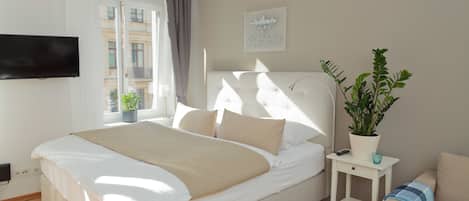 A neatly arranged bedroom with a bed, bedside table, and a potted plant.