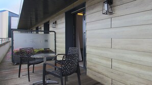Un área de estar al aire libre con una mesa y sillas, una terraza de madera y la entrada de un edificio.