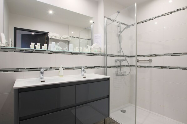 Un baño moderno con ducha de vidrio, tocador doble y un espejo grande.