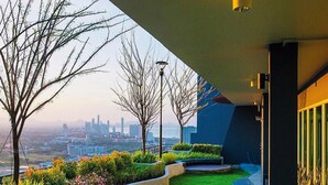 A modern building with a landscaped garden, a view of a city skyline, and a clear sky. - Supalai Mare Pattaya Condo Sea View by Dome (Pattaya)