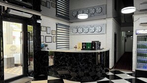 A lobby with a checkered floor, a reception desk, and multiple clocks on the wall. - Orzu Hotel (Tashkent)