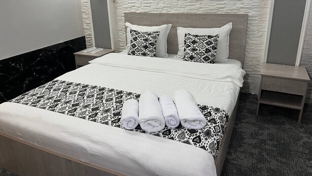 A hotel room with a bed, two nightstands, a headboard, and a patterned bedspread. - Orzu Hotel (Tashkent)