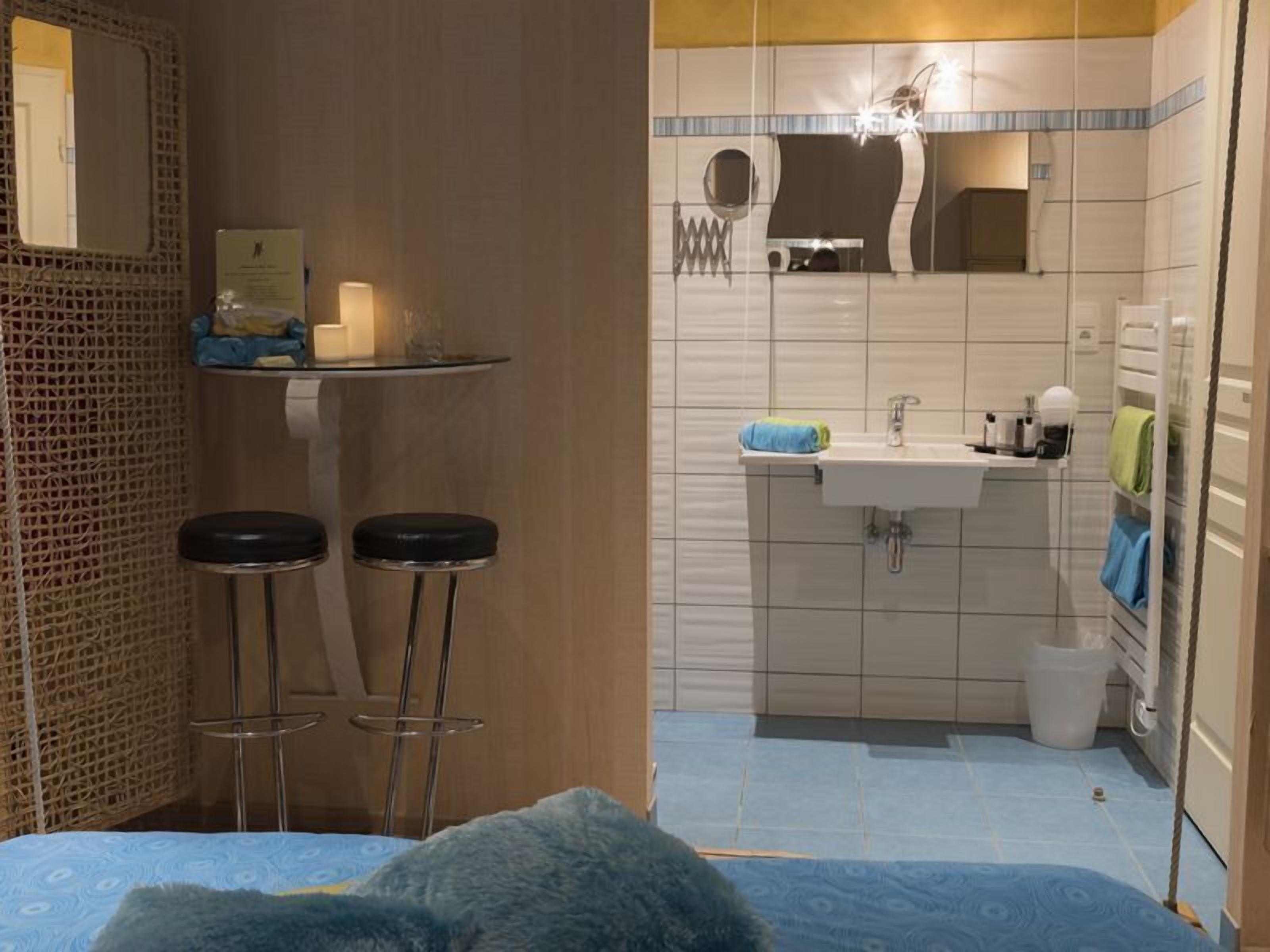 A bathroom with a sink, mirror, and two stools.