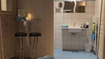 A bathroom with a sink, mirror, and two stools.