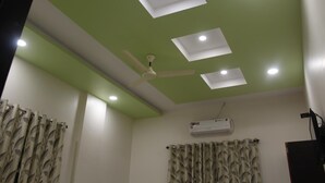 A room with a green ceiling, recessed lighting, a ceiling fan, and patterned curtains. - Hotel Radhika Inn (Trimbak)