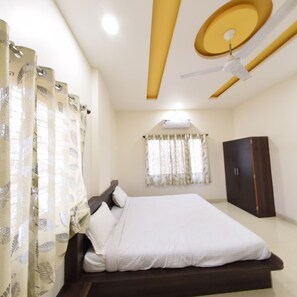 A bedroom with a bed, curtains, a wardrobe, and a ceiling fan.