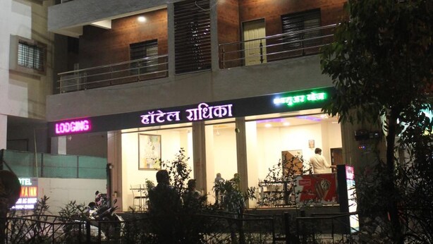 A multi-story hotel with a modern design, featuring balconies on each floor and a well-lit entrance. - Hotel Radhika Inn (Trimbak)