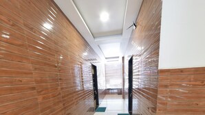 A modern hallway with wooden paneling on the walls and a shiny tiled floor. - Hotel Radhika Inn (Trimbak)