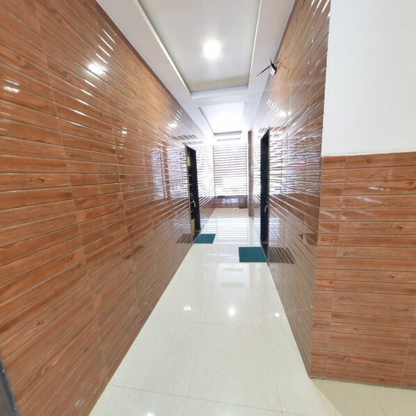 A modern hallway with wooden paneling on the walls and a shiny tiled floor.