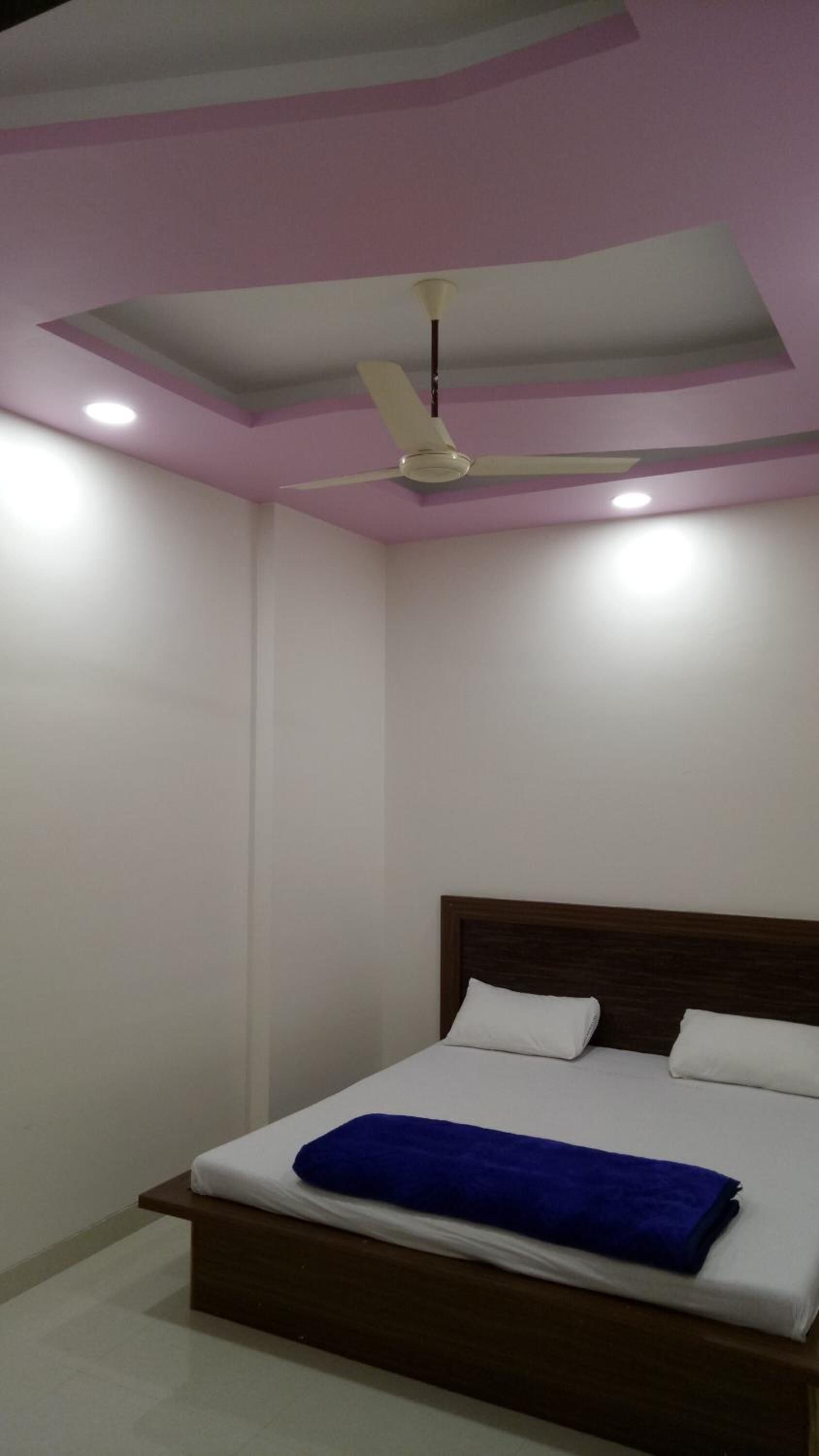 A bedroom with a bed, a ceiling fan, and recessed lighting.