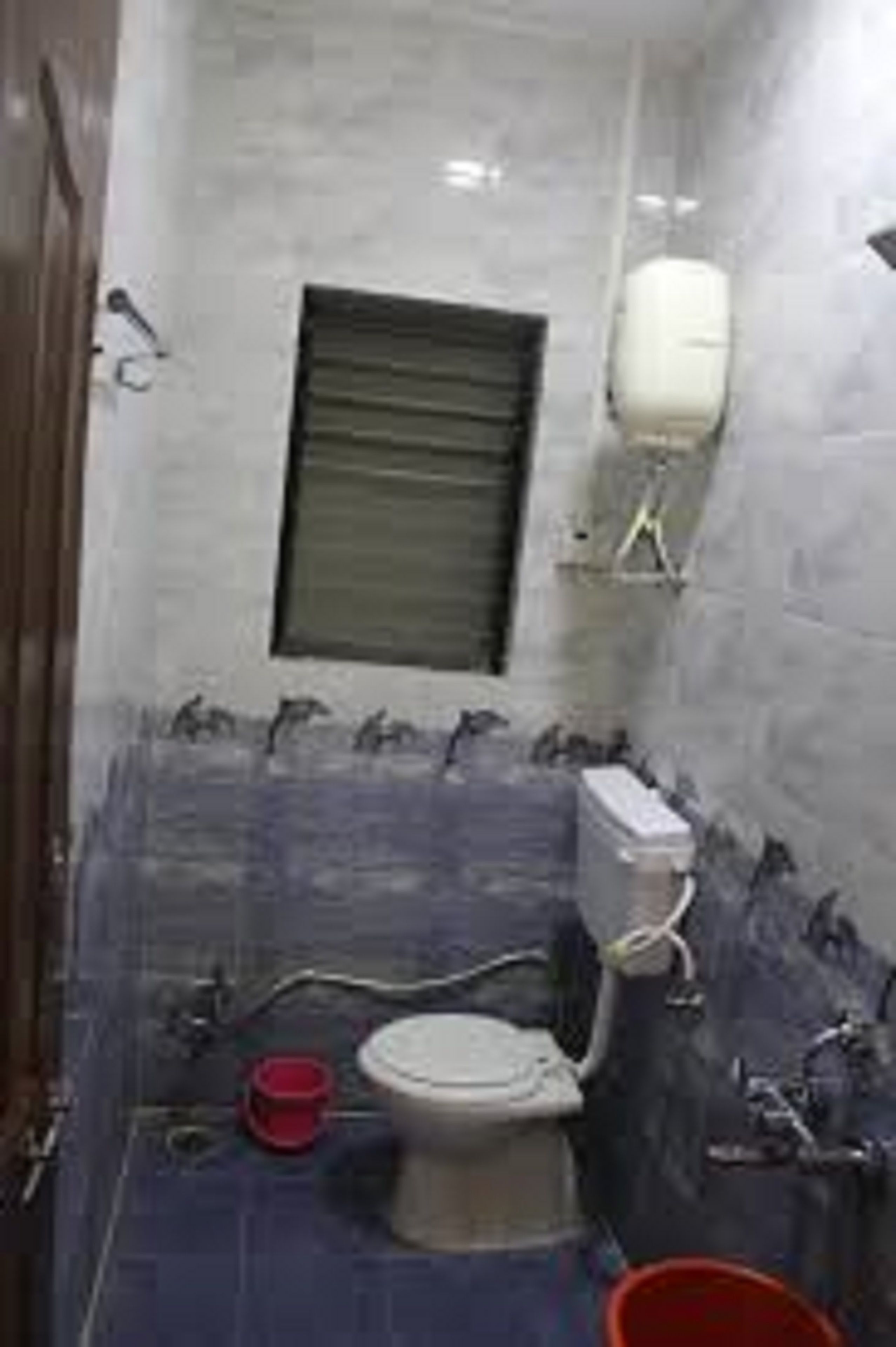 Une petite salle de bain avec des toilettes, une fenêtre et un lavabo.
